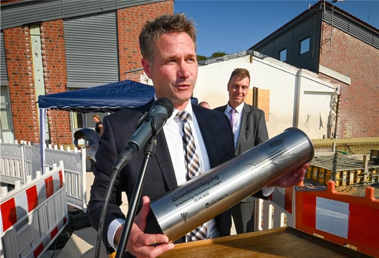 Langener Gymnasium: Erweiterungsbau schreitet voran Kai-Oliver Becker von der Firma Goldbeck hält die Kapsel mit den Wünschen der Schüler in den Händen. Später soll die Kapsel wieder ausgegraben und ausgestellt werden.