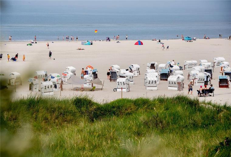 Ein Nordsee-Strand mit Strandkörben. Im Hintergrund ist das Meer zu sehen.