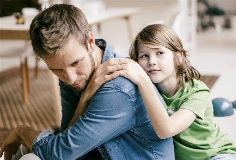 Bremen: "Elterntraining" soll Kindern bei Trennungen helfen Ein Kind lehnt sich an den Rücken seines Vaters. Der Mann legt seine Hand über die Hand des Kindes.