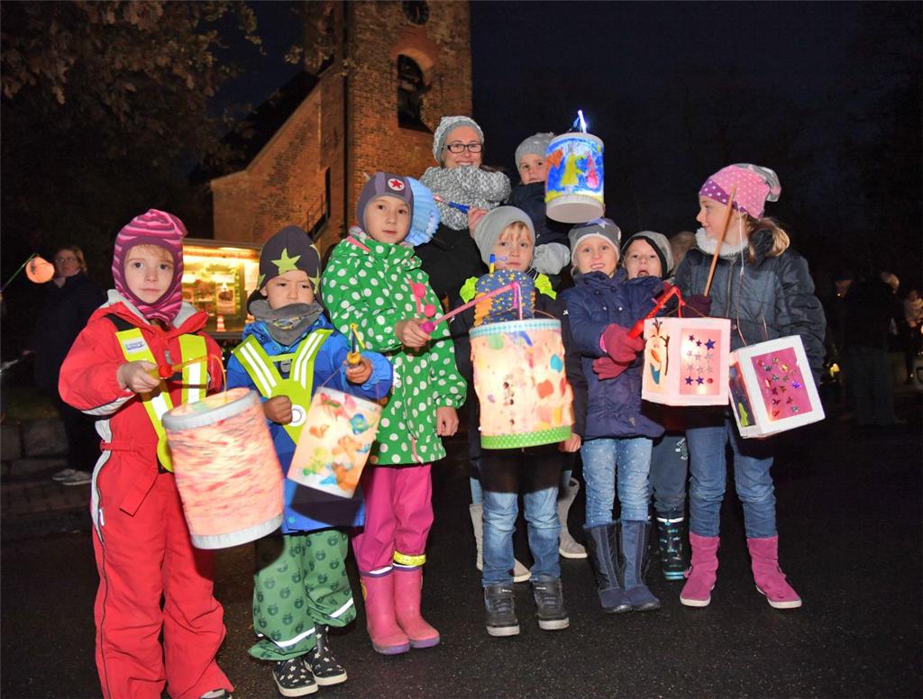 Kinder, Eltern und Mitarbeiter die Kita Regenbogen zogen mit ihren Laternen durc...