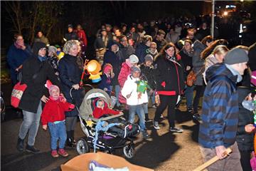 Kinder, Eltern und Mitarbeiter die Kita Regenbogen zogen mit ihren Laternen durc...