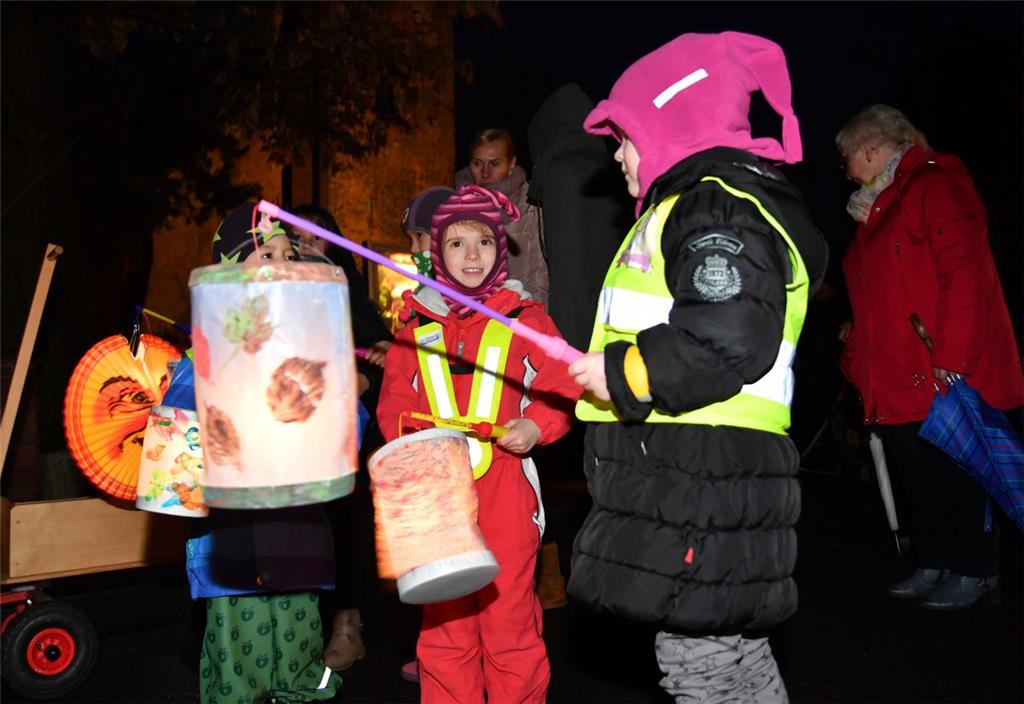 Kinder, Eltern und Mitarbeiter die Kita Regenbogen zogen mit ihren Laternen durc...