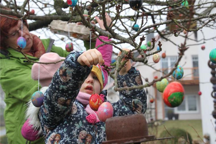 Tarmstedt: Leute freuen sich über bunten Osterbaum Kinder helfen dabei, die vielen bunten Ostereier in die Japanische Kirsche zu hängen.