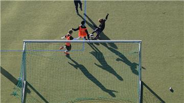 Kinder spielen vor einem Tor mit einem Fußball. 