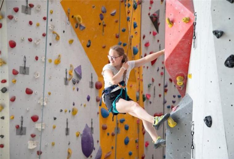 Klettern gegen Bluthochdruck Junge Frau an einer Bowlderwand