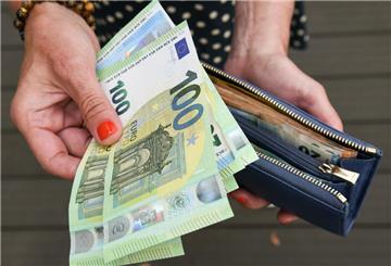 Eine Frau hält eine Geldbörse in der einen und mehrere 100-Euro-Scheine in der anderen Hand. Das Klimageld versprach bis zu 1000 Euro pro Familie, doch nun kommt es doch nicht.