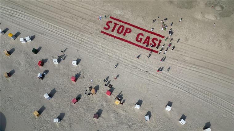 Klimaschutzaktivisten von Fridays for Future schreiben ihre Forderung nach einem Ende der Gasförderung auf den Strand der Insel Borkum. 