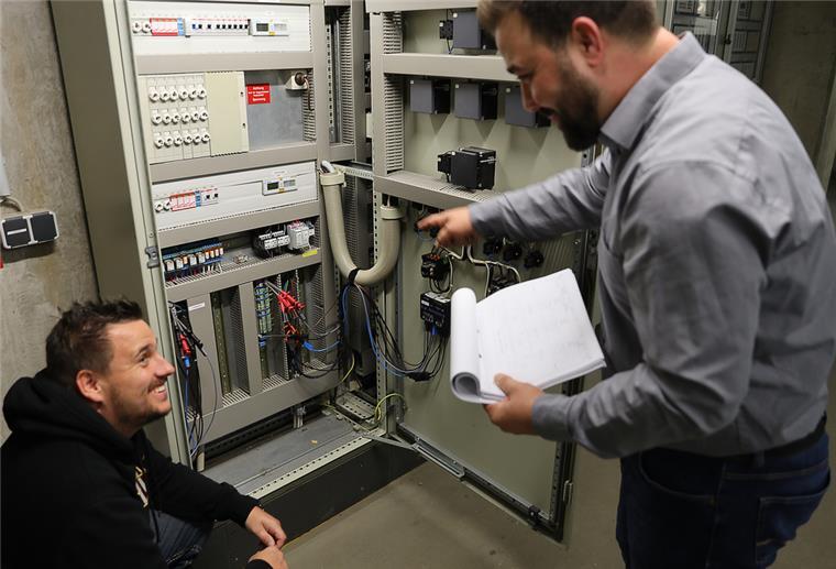 Klimaschutzmanager Julian Fricke (rechts) und Elektromeister Marcel Holtmann kontrollieren Stromlogger, die den Stromverbrauch detailliert erfassen.