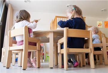 Die Kinder einer Kindergrippe sitzen während des Mittagessens an einem Tisch.