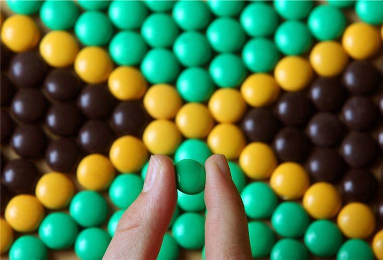 Parteien im Kreistag auf der Suche nach Mehrheiten Ein junges Mädchen legt aus schwarzen, gelben und grünen "Smarties" die Fahne von Jamaika.