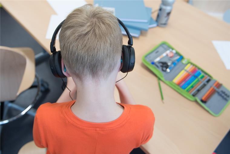Lieber mit Limit: Kopfhörerlautstärke am Smartphone begrenzen Ein Schüler in einem Klassenzimmer und trägt Kopfhörer.