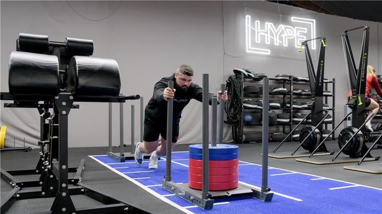 Er wirft Steine wie Obelix: Lucas Underwood stellt als Strongman Rekorde auf Ein Mann schiebt einen Schlitten mit Gewichtsscheiben.