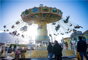 Besucher des Bremer Freimarkts sitzen im Kettenkarussell. Davor stehen andere Besucher und schauen zu.