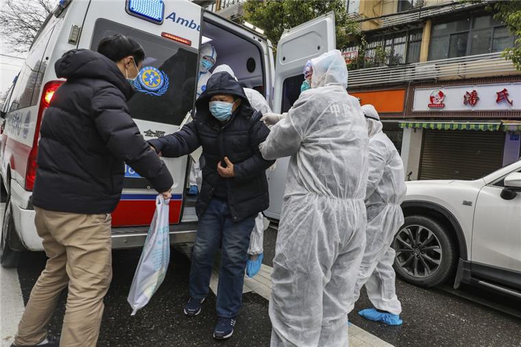Krankenhausmitarbeiter in Schutzkleidung helfen einem Patienten in Wuhan aus einem Krankenwagen. Angesichts der starken Ausbreitung der neuen Lungenkrankheit hat China seine Maßnahmen am Wochenende deutlich verschärft.