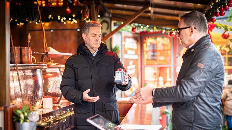 Unterwegs mit Niedersachsens Glühwein-Kontrolleur Kröning (l.) übergibt eine Probe Feuerzangenbowle an den Lebensmittelkontrolleur der Stadt Hannover, Thomas Rautenberg.