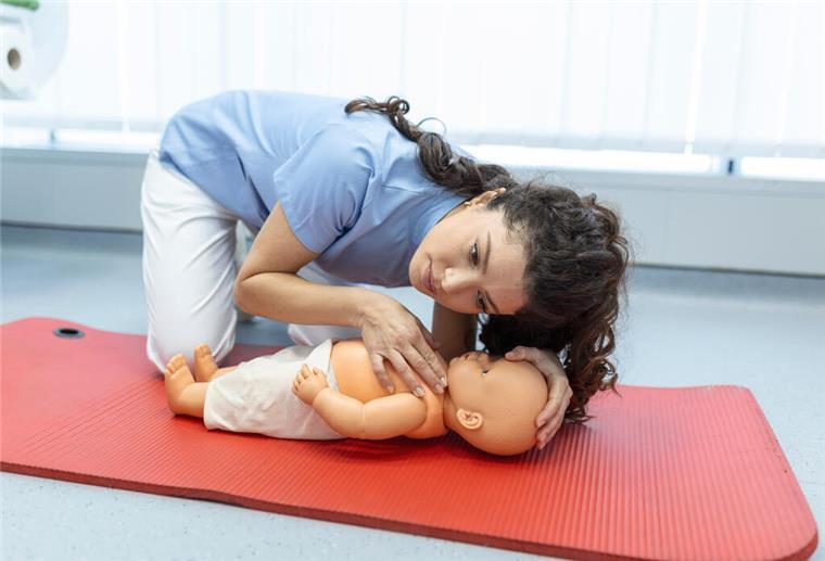 Frau mit Erste-Hilfe-Kinderpuppe