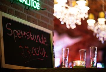 Kurz vor der Sperrstunde stehen neben einem Kreideschild mit der Aufschrift: „Sperrstunde 23:00 Uhr" drei leere Gläser Bier auf einem Tisch.