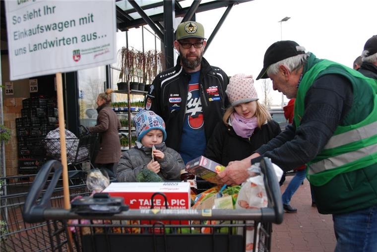 Hagen: Bauern suchen das Gespräch mit Bürgern Landvolk-Mitarbeiter Arno Müller aus Schiffdorf erläutert den Bürgern in Hagen, dass die heimische Landwirtschaft an vielen Produkten des täglichen Einkaufs beteiligt ist. Auch Alex Klein aus Wulsbüttel sowie Sohn Lias (links) und Tochter Danica hören aufmerksam zu.