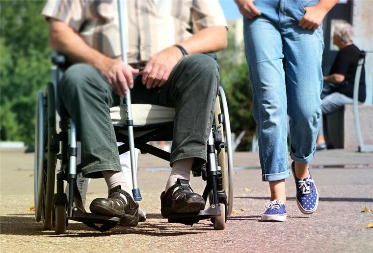 Person im Rollstuhl mit Pflegerin