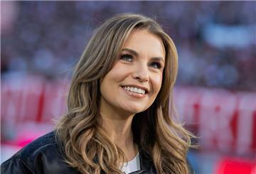 Laura Wontorra lächelt für die Kamera. Sie steht in einem Fußballstadion.