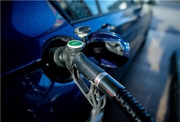 Eine Zapfpistole mit der Aufschrift „Super“ steckt an einer Tankstelle in der Tanköffnung eines Fahrzeugs. 