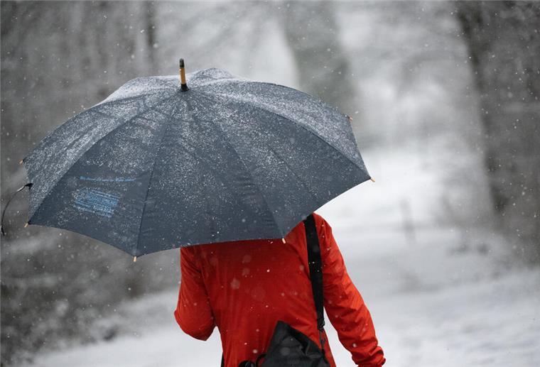 Wetter: Bald gibt es wieder Schnee in Bremerhaven Eine Frau geht mit Regenschirm durch den Schnee.