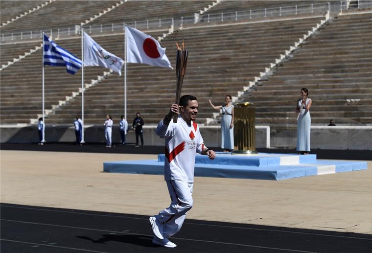 US-Leichtathleten fordern Verschiebung der Olympischen Spiele Lefteris Petrounias, griechischer Olympiasieger im Kunstturnen, läuft mit der Fackel während der Übergabe des olympischen Feuers an die Organisatoren der Sommerspiele von Tokio 2020.