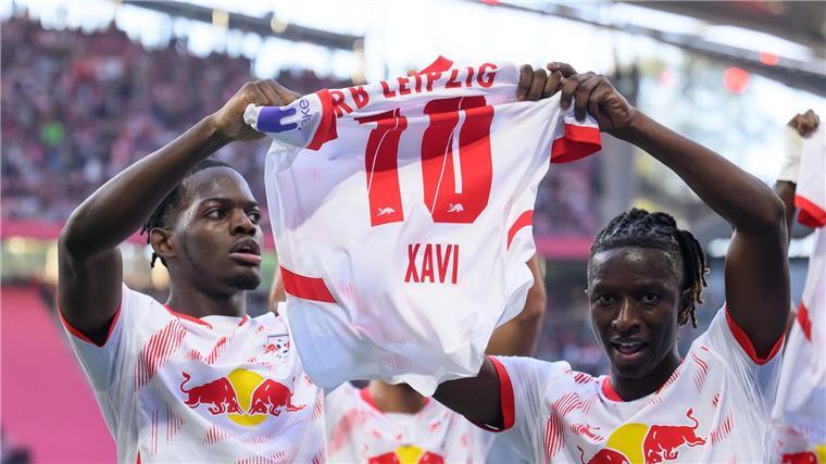 Leipzig bangt nach Freiburg-Sieg um Torhüter Gulacsi Leipzigs Castello Lukeba (l) und Amadou Haidara halten nach dem 2:1 ein Trikot des verletzten Xavi Simons nach oben.