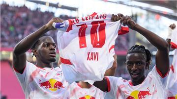 Leipzigs Castello Lukeba (l) und Amadou Haidara halten nach dem 2:1 ein Trikot des verletzten Xavi Simons nach oben.