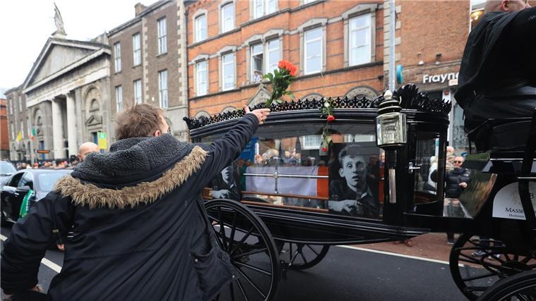 Trauerfeier für Pogues-Sänger Shane MacGowan Letzter Abschied: Passanten werfen Blumen auf den Leichenwagen.