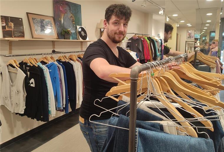 Nachhaltige Mode: Fast Fashion war gestern Lukas Seidel sortiert gebrauchte Kleidung auf Kleiderbügel in einem Ladengeschäft.