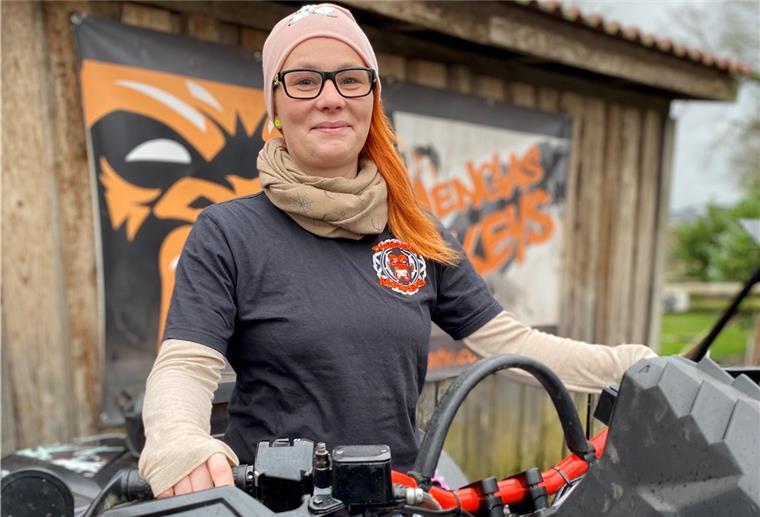 Lintigerin will Miss Quad 2022 werden Eine junge Frau sitzt auf ihrem Quad. Sie hat rote Haare und trägt ein schwarzes T-Shirt und eine rosa Mütze.