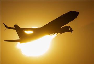 Eine Passagiermaschine fliegt nach ihrem Start vom Flughafen Frankfurt an der untergehenden Sonne vorbei.