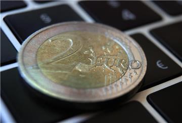 Eine Zwei -Euro-Münze liegt auf der Tastatur eines Laptops neben einem Eurozeichen.