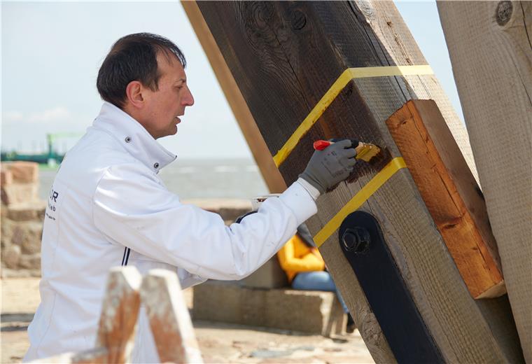 Cuxhaven sucht nach Schutzanstrich für Kugelbake Manuel Ferreira Pájaro trägt Wurzelteer auf einen mit Klebeband markierten Testabschnitt auf.