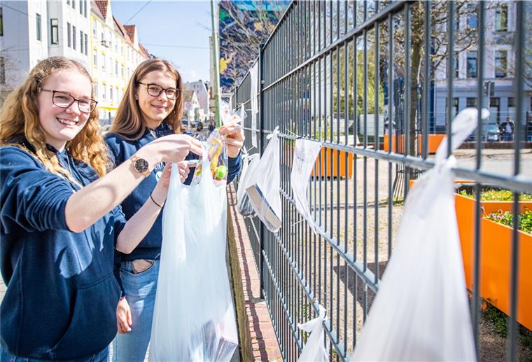 „Sag uns, was du gerade brauchst“ Marie Speckmann (links) und Rieke Klemm, hängen Lebensmittel an den Gabenzaun für Bedürftige.