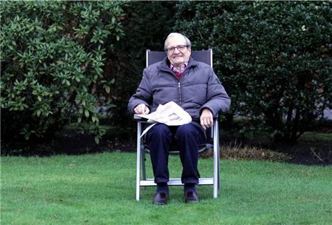 Ein Mann sitzt im Garten in einem Stuhl