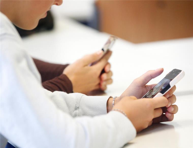 Schülerinnen benutzen ihr Smartphone im Unterricht.  Medienpädagogen fordern: Schulen sollten Smartphones sinnvoll einbinden statt verbieten.