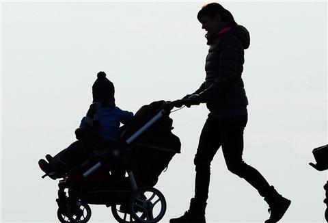 Eine Frau schiebt einen Kinderwagen mit ihrem Kind.