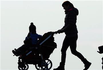Eine Frau schiebt einen Kinderwagen mit ihrem Kind.
