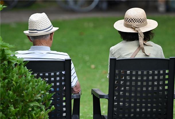 Ein älteres Paar verfolgt im Kurpark das Konzert eines Schulorchesters. 