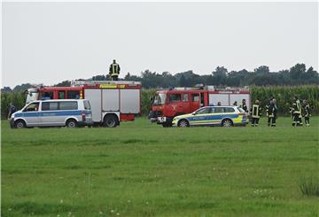 Das Bild zeigt Einsatzkräfte von Polizei und Feuerwehr vor einem Maisfeld.