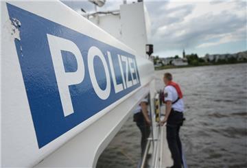 Ein Mann steht auf einem Boot mit dem Schriftzug Polizei.