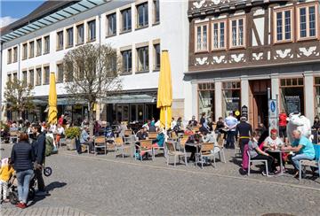 Menschen besuchen die Außenbereiche der Cafés und Restaurants auf einem Marktplatz.