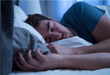 Ein Mann schläft seitlich im Bett