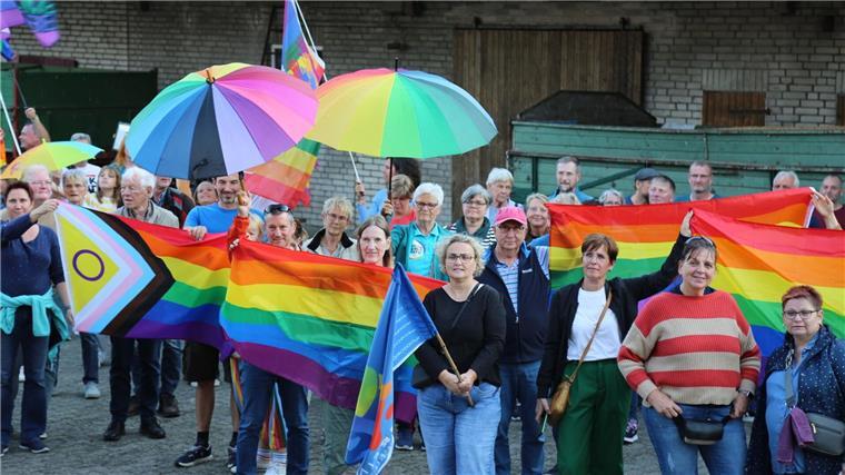 Aus Solidarität: Bürger wollen Dorf mit Fahnen bunt machen Menschen mit Regenbogenflaggen und -schirmen beteiligten sich an einer Kundgebung.