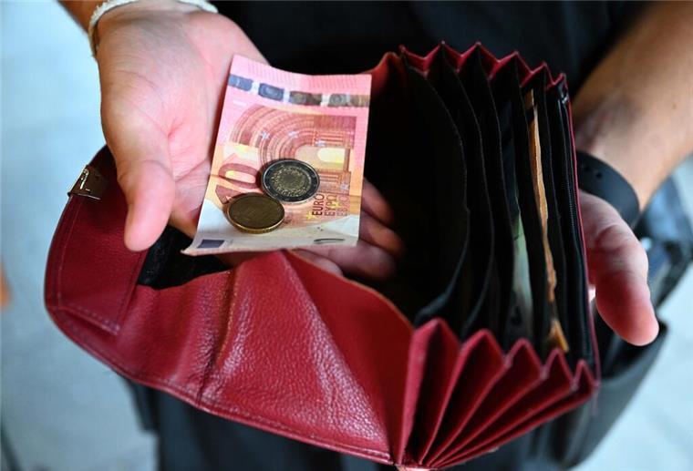 Ein Kellner eines Restaurants hält einen Geldbeutel in der Hand, während er in der anderen Hand Geld hält. Minijobber dürfen ab 2026 rund 50 Euro mehr im Monat verdienen – rund 603 Euro. Ein Jahr später steigt die Grenze erneut.