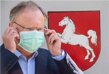 Ministerpräsident Stephan Weil zieht einen Mundschutz über. Seine Landesregierung verfährt bei weiteren Lockerungen vorsichtig.