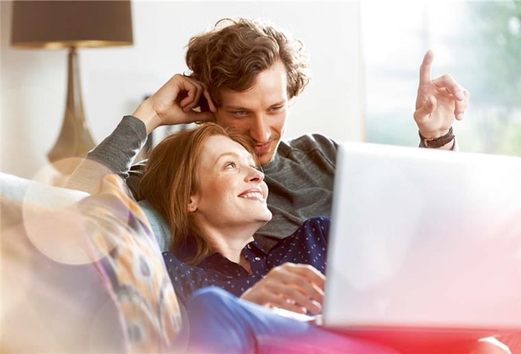 Innovative Baufinanzierung: So geht's! Paar sitzt mit Laptop auf dem Sofa und plant seine Zukunft
