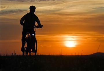 Ein Mann fährt mit einem Fahrrad kurz nach Sonnenaufgang über einen Feldweg